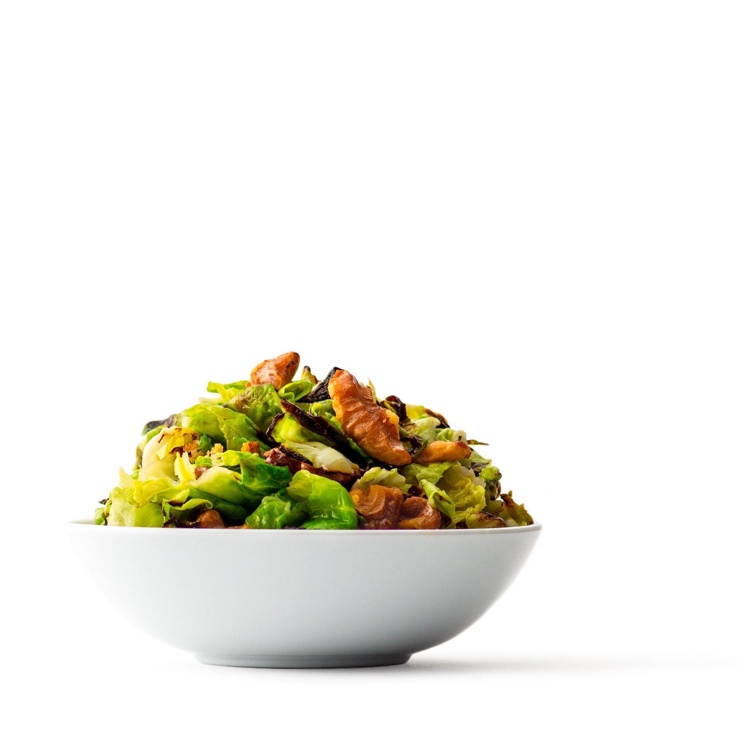 brussel sprouts and walnuts tossed together in a white bowl