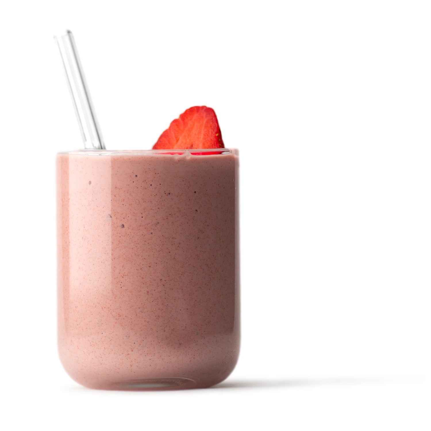 pink smoothie in clear glass cup with glass straw and sliced strawberry