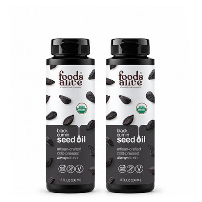 Two 8 oz black plastic bottles of Foods Alive Organic Black Cumin Seed Oil with white and charcoal labels featuring black cumin seeds. 
