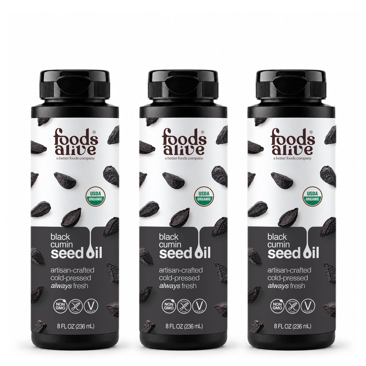 Three 8 oz black plastic bottles of Foods Alive Organic Black Cumin Seed Oil with white and charcoal labels featuring black cumin seeds. 
